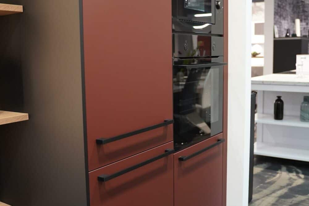 Wandschrank in rot mit Stangengriffen und Elektrogeräten